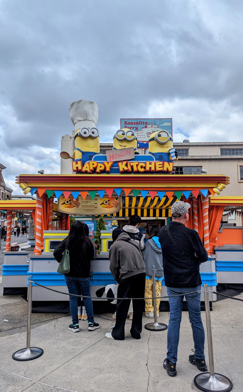 Puesto de comida Happy Kitchen con figuras de los Minions sobre el techo.