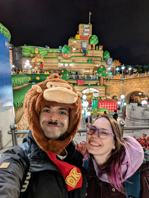 Pablo, autor de Vamos Pa' Japón, y su esposa haciéndose una selfie de noche en Super Nintendo World; él lleva un gorro de Donkey Kong.
