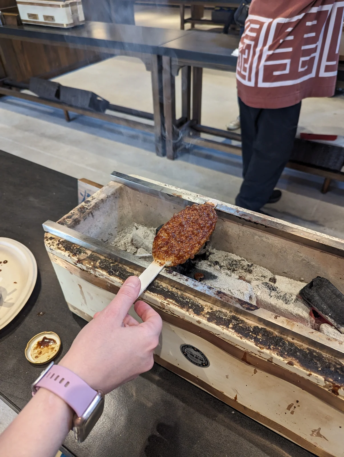 Gohei-mochi asándose sobre las brasas en Tatara-ba, en Mononoke Village de Ghibli Park